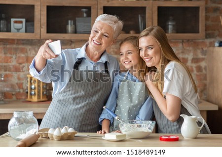Happy female family taking selfie on smartphone while baking at kitchen, copy space