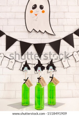 Creative children green Halloween cocktails with cute paper ghost over bricks wall