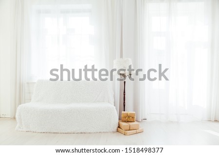 white sofa with gifts in the interior of the white room with windows