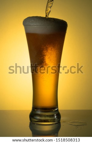 beer with foam on yellow background
