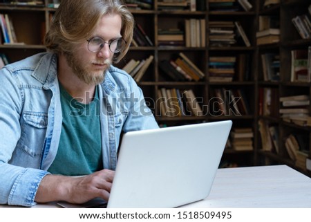 Serious man student using laptop looking at computer screen typing e learning internet course focused on study online in app think on work task doing project research sit at library desk, copy space Royalty-Free Stock Photo #1518509495