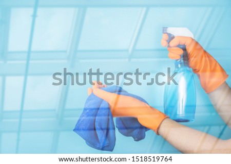 The cleaning lady shows spray and blue cloth on blurred background.