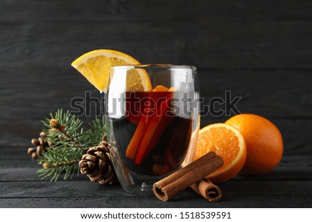 Glass of tasty mulled with orange on decorated background, space for text