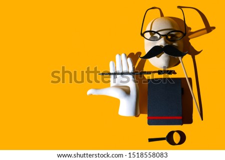 composition of various objects. Glasses, magnifying glass, pencil, mustache, butterfly, hand, notebook, mask. Form the image of a business person. Hard shadows on yellow background