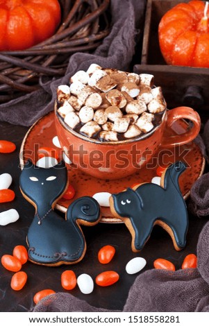 Homemade gingerbread cookies in the form of black cаts and hot chocolate mug for  Halloween holiday, selective focus  with shallow depth of field
