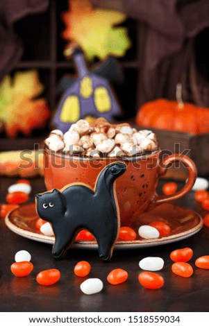Mug filled with hot chocolate and marshmallows and Halloween gingerbread cookies, tasty Halloween food concept 