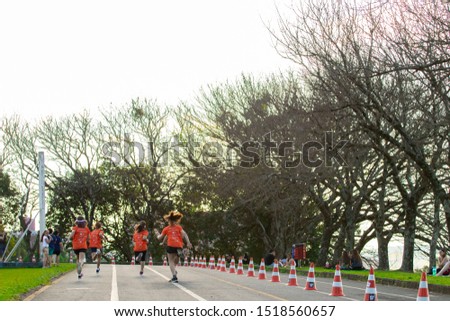 Group of children running on a competition in the park surrounded by trees.