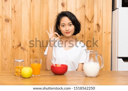 Asian young woman having breakfast milk showing an ok sign with fingers