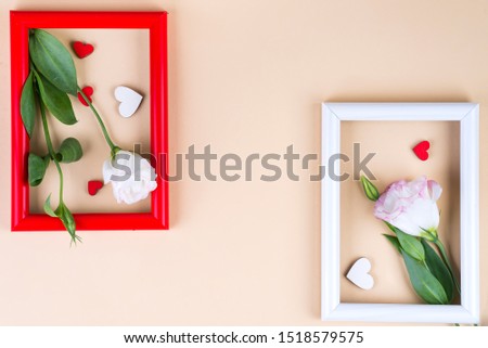 Empty color frames, red hearts and flowers eustoma on beige paper background with copy space. Love concept