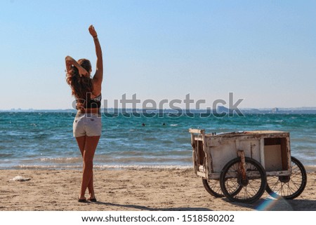 Woman alone with beach seller car at the beach looking over the horizon with  wavy sea on a wind day in Mediterranean