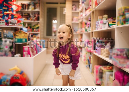 Adorable little girl shopping for toys. Cute female in toy store. Happy young girl selecting toy Royalty-Free Stock Photo #1518580367