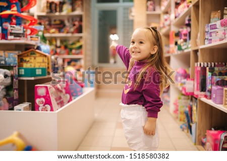 Adorable little girl shopping for toys. Cute female in toy store. Happy young girl selecting toy Royalty-Free Stock Photo #1518580382