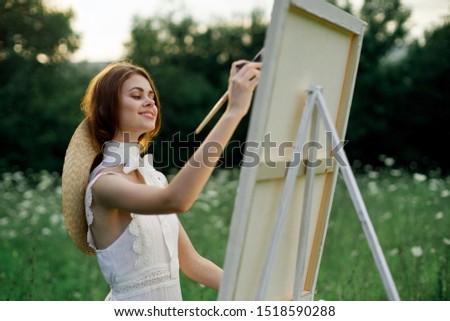 beautiful easel woman with hard hat paints in the forest