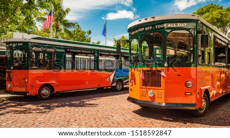 Tourists  travel on historic, orange Trolley Buses of Key West, Florida Royalty-Free Stock Photo #1518592847