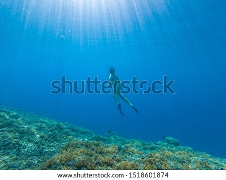 Young woman freediving in a clear sea over coral reef in Gili Meno Indonesia