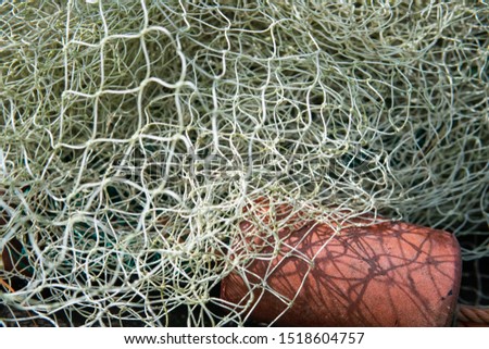 A mesh of white and orange fishing net in the summer sun.