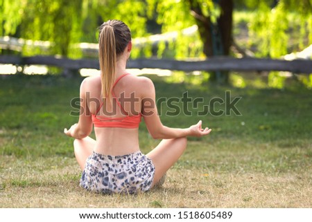 Young slim girl doing yoga exercises in the park.