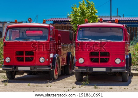 two old red fire trucks standing in parallel