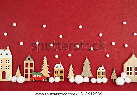 Christmas composition with toy  wooden houses over the red background. Seasonal holidays, greeting card, invitation for xmas party concept. Flat lay. Top view