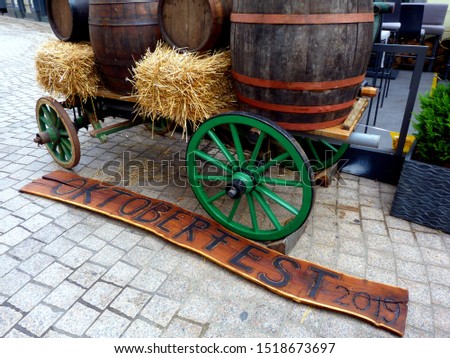 street decoration in downtown Zagreb, Croatia for Oktoberfest with carriage, straw bales, wooden barrels and wooden signage. festival scene. grey cobblestone street paving in the inner city.  