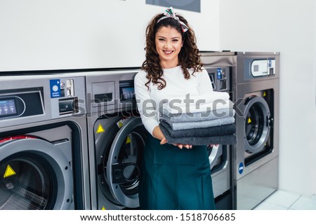 Beautiful female employee working at laundromat shop. Royalty-Free Stock Photo #1518706685