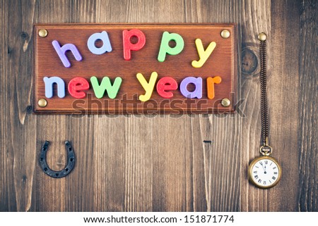 Happy New Year sign board, watches, horse shoe on old wood wall background