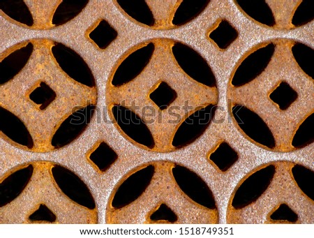 Rusted cast iron storm grate in beautiful Moorish or Celtic design with repeating circular pattern.