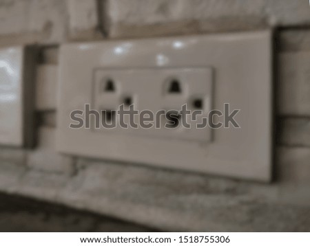 Gray tone picture, Blurred photo, Electricity outlet on the wall that's covered with safety plugs. Protection baby form playing with plug. Safety first concept. Covering plug holes of the surge protec