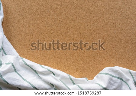 close up top view white color with green line pattern fabric tablecloth on vintage cork wood texture tabletop in kitchen background with sepia tone for design  concept