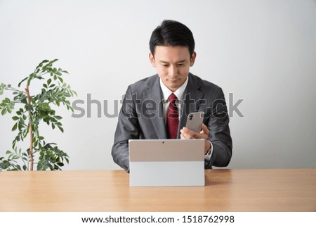 Businessman using a computer while looking at a smartphone