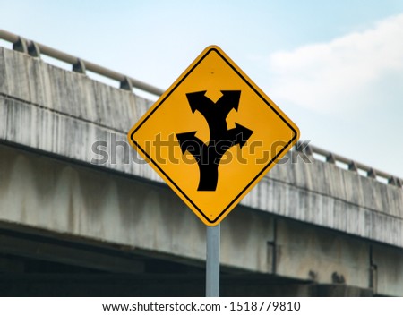 Road sign with arrows informs about complicated crossing on the road. Warning of junction with many course of way.