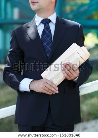 Close up of the hands of the businessman with a newspaper. Outdoors