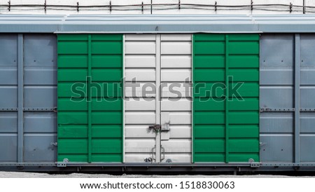 Front view of a container train freight car with a large metal lock with the national flag of Nigeria.The concept of export-import,transportation, national delivery of goods and rail transportation
