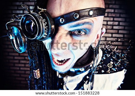 Portrait of a steampunk man with a mechanical devices over brick wall.
