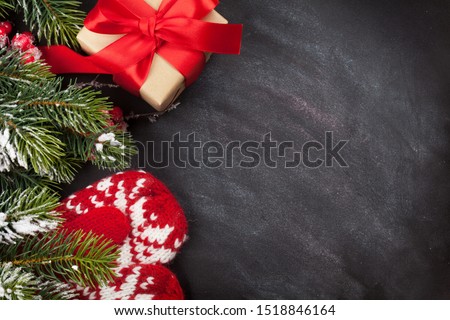 Christmas greeting card with gift box and fir tree branch over blackboard texture background. Xmas backdrop. Top view with copy space for your greetings