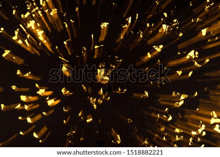 Gold confetti on black background. Flat lay, top view. Long exposure.