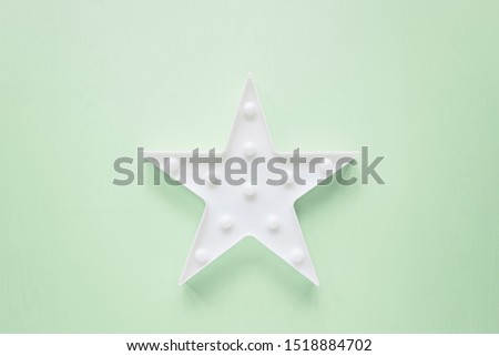 Star shaped white LED lights lamp single frame. Creative conceptual top view flat lay composition with copy space on mint green color background in minimal style. Overhead, template, mockup