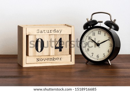 Wood calendar with date and old clock. Saturday 4 November