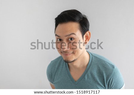 Happy Asian man is smiling with hidden motive face on grey background.