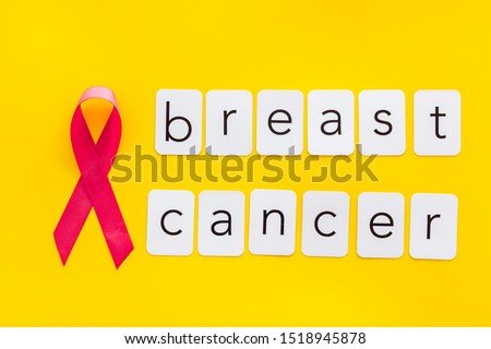 Pink ribbon as symbol of breast cancer awareness on yellow background top view