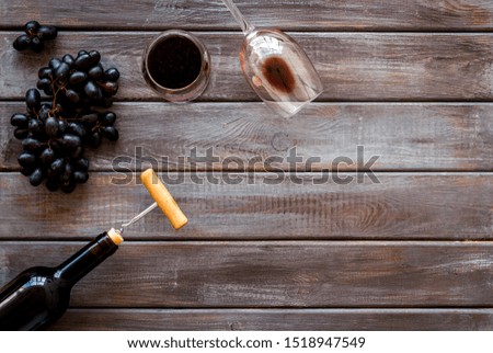 Red wine bottle near wineglass on dark wooden background top view copy space