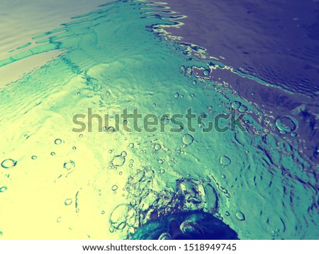 Woman hair with goggles under water pool with abstract colorful bubbles surface texture background, water sport concept, unrecognised person.