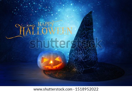 holidays concept of Halloween . Pumpkin and witch hat over wooden table at night scary, haunted and misty forest
