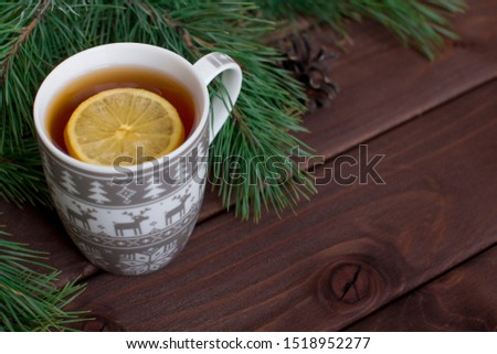 christmas mug with hot tea witha a slice of lemon on a dark brown wooden background