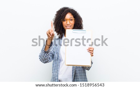 young pretty black woman with a sheet of paper against white wall