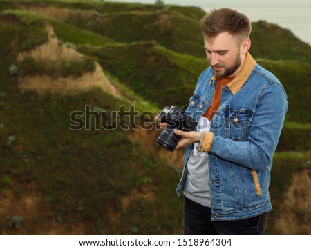 Male photographer with professional camera on green hill