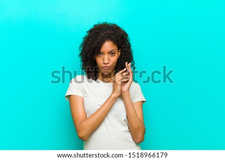 young black woman feeling proud, mischievous and arrogant while scheming an evil plan or thinking of a trick against blue wall
