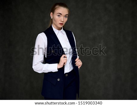 Portrait of a pretty manager girl in a business suit on a gray background with long hair. Great makeup, beautiful face. It is in different poses with different emotions.