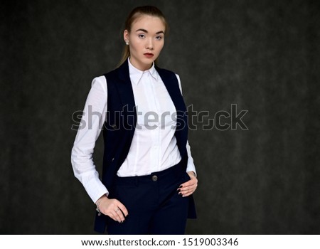 Portrait of a pretty manager girl in a business suit on a gray background with long hair. Great makeup, beautiful face. It is in different poses with different emotions.