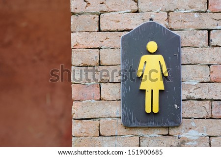 Ladies bathroom sign on a brick wall.